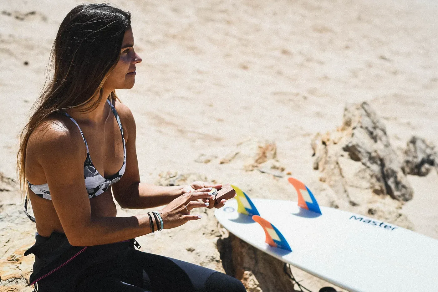 Surfista aplicándose Selva Brava en la playa, junto a su tabla